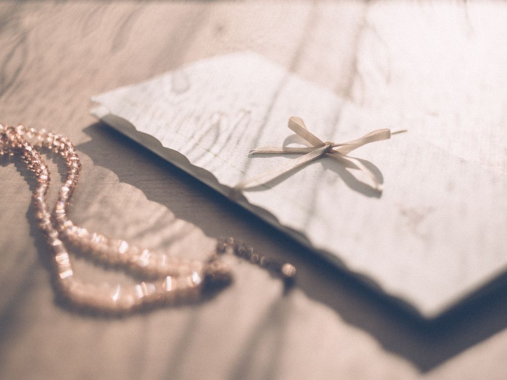 Invitation Card next to pearl necklace